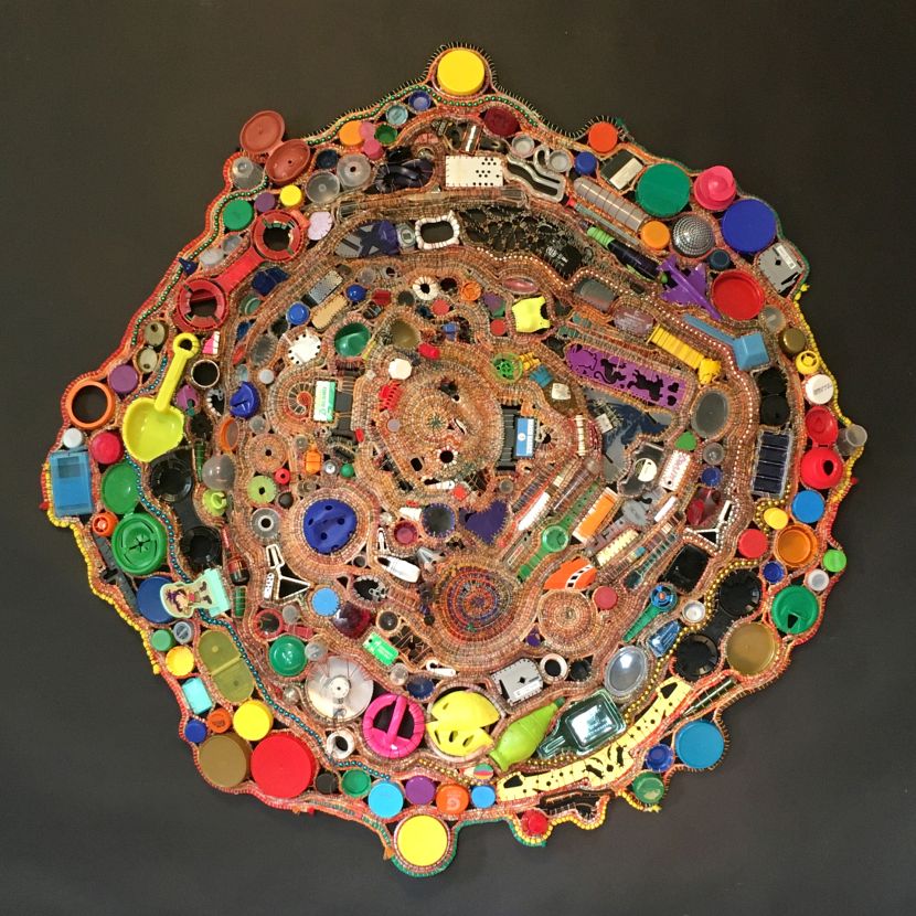 Coiled basketry wall piece incorporating discarded plastic items.